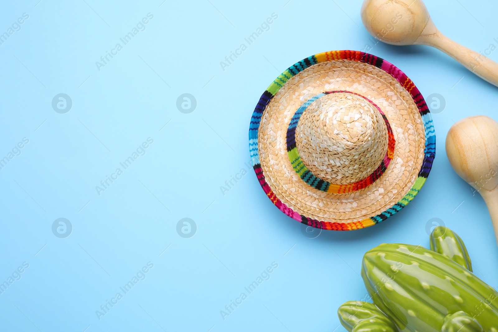 Photo of Wooden maracas, toy cactus and sombrero hat on light blue background, flat lay with space for text. Musical instrument