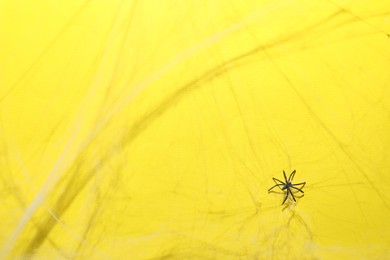 Photo of Cobweb and spider on yellow background, top view