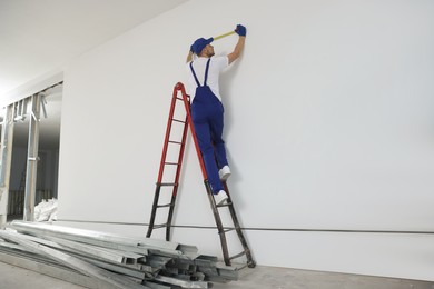 Photo of Construction worker using measuring tape in room prepared for renovation