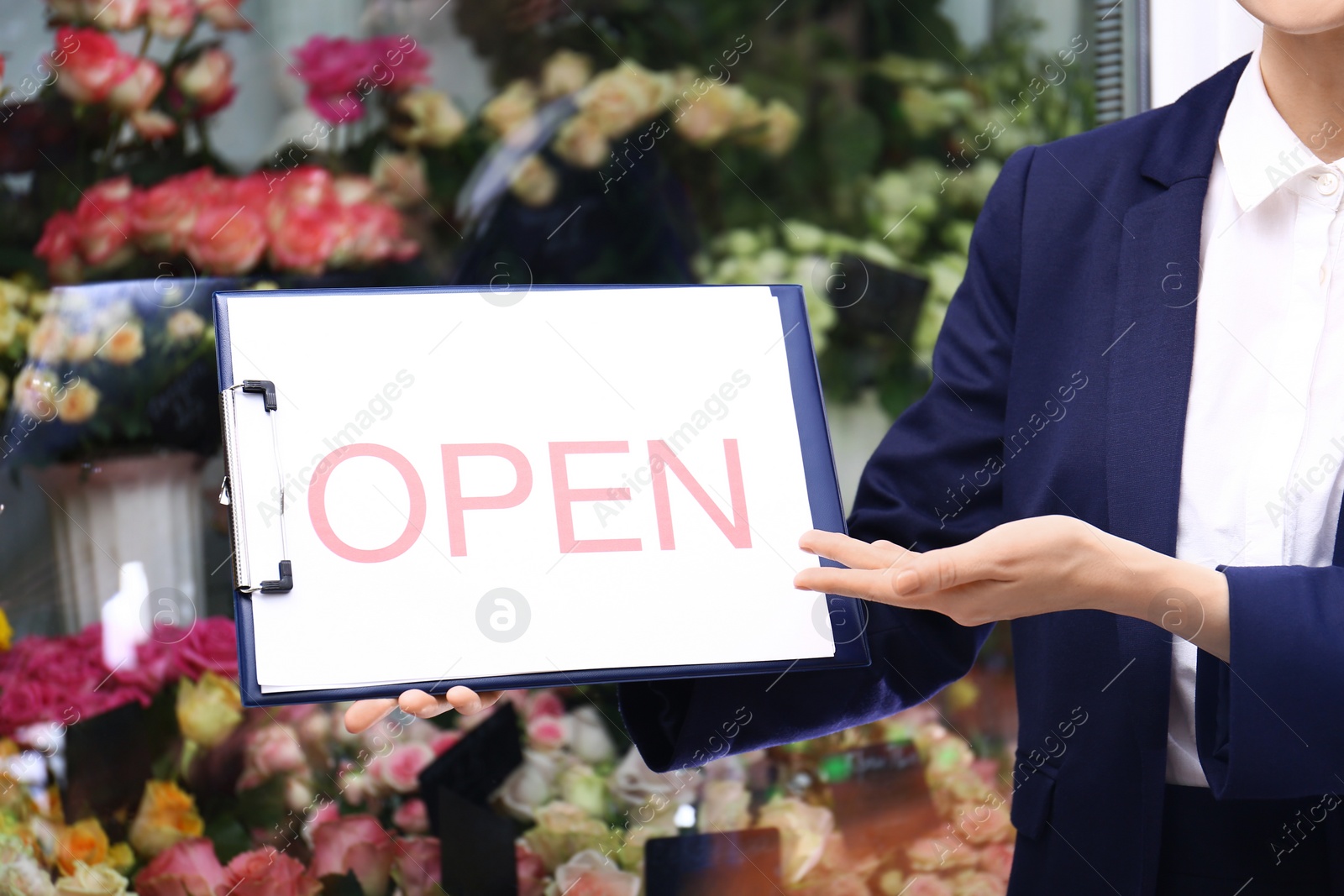 Photo of Female business owner holding OPEN sign near flower shop, closeup