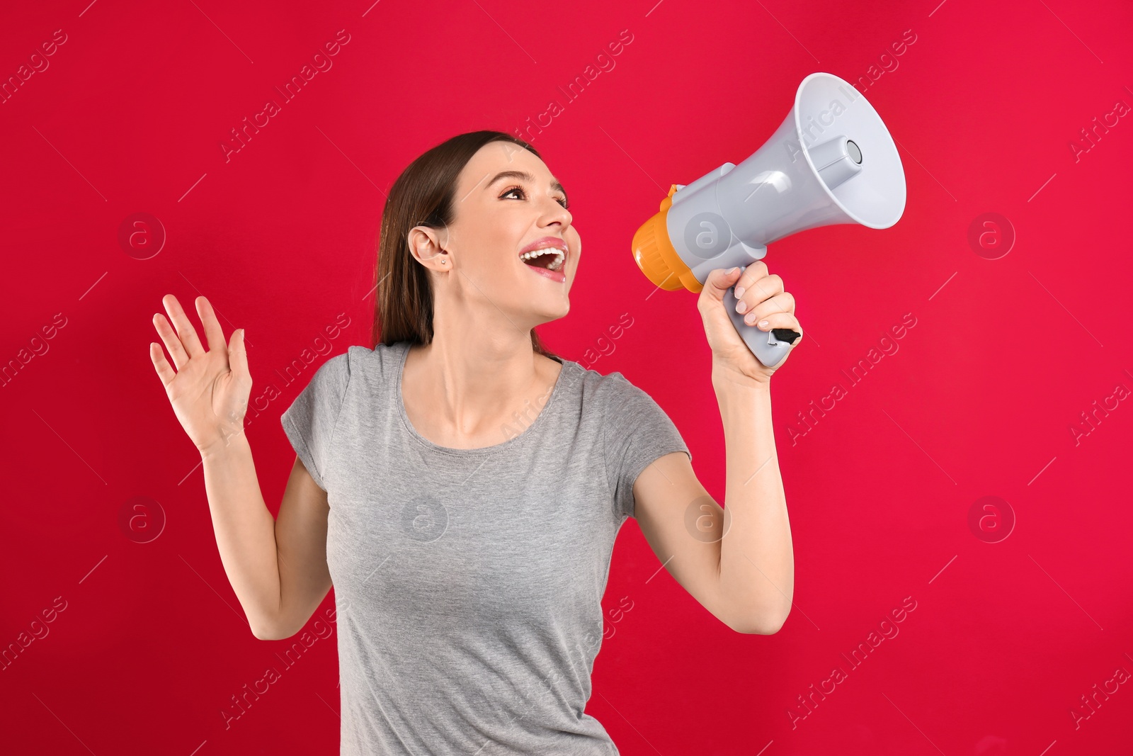 Photo of Young woman with megaphone on red background