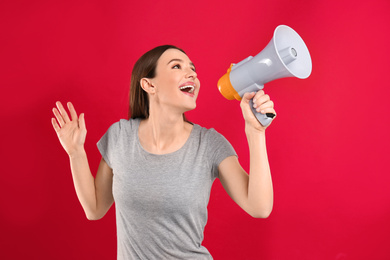 Photo of Young woman with megaphone on red background