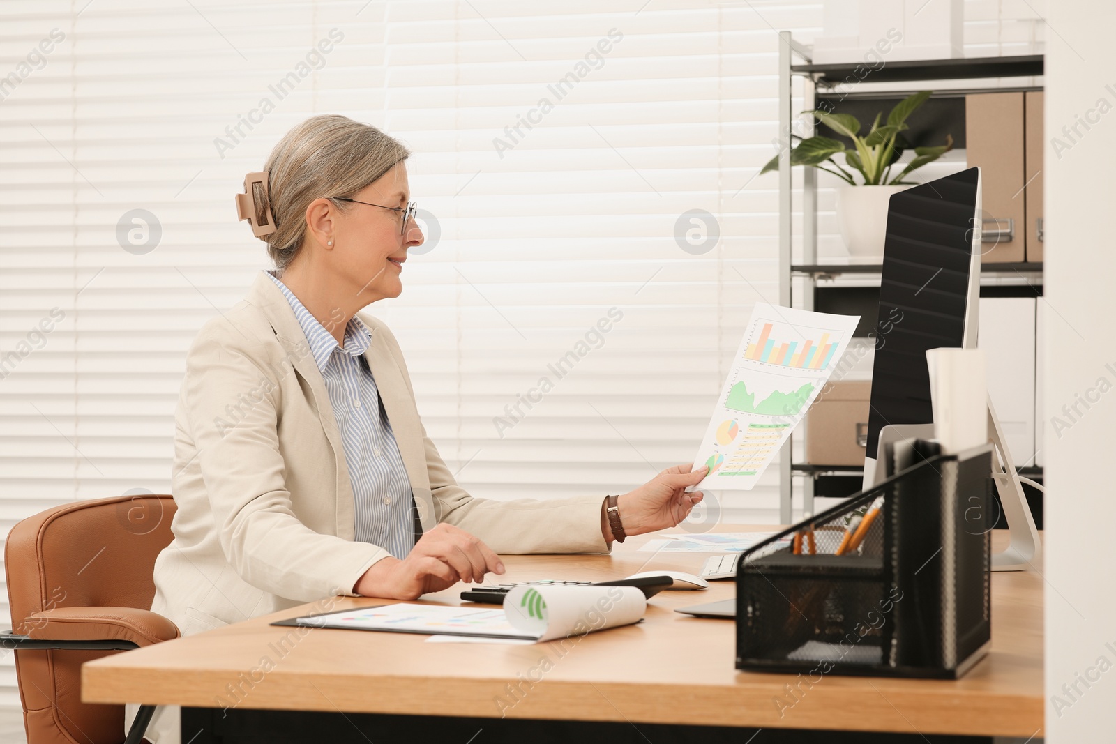 Photo of Senior accountant working at wooden desk in office