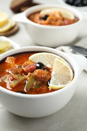 Photo of Meat solyanka soup with sausages, olives and vegetables on white table, closeup