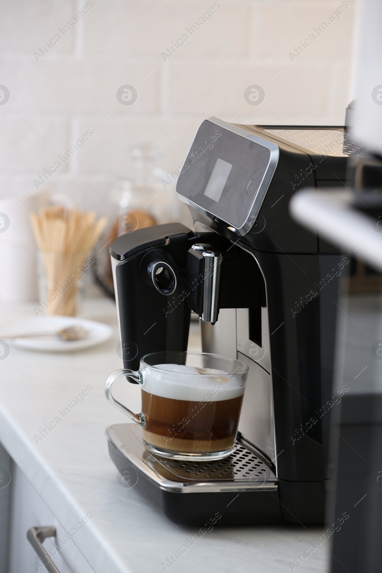 Photo of Modern coffee machine with glass cup of latte on white marble countertop in kitchen