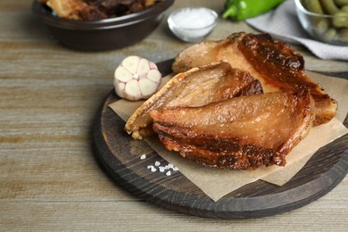 Photo of Tasty fried cracklings on wooden table. Cooked pork lard