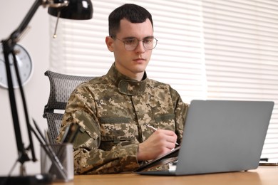 Military service. Young soldier working at table in office
