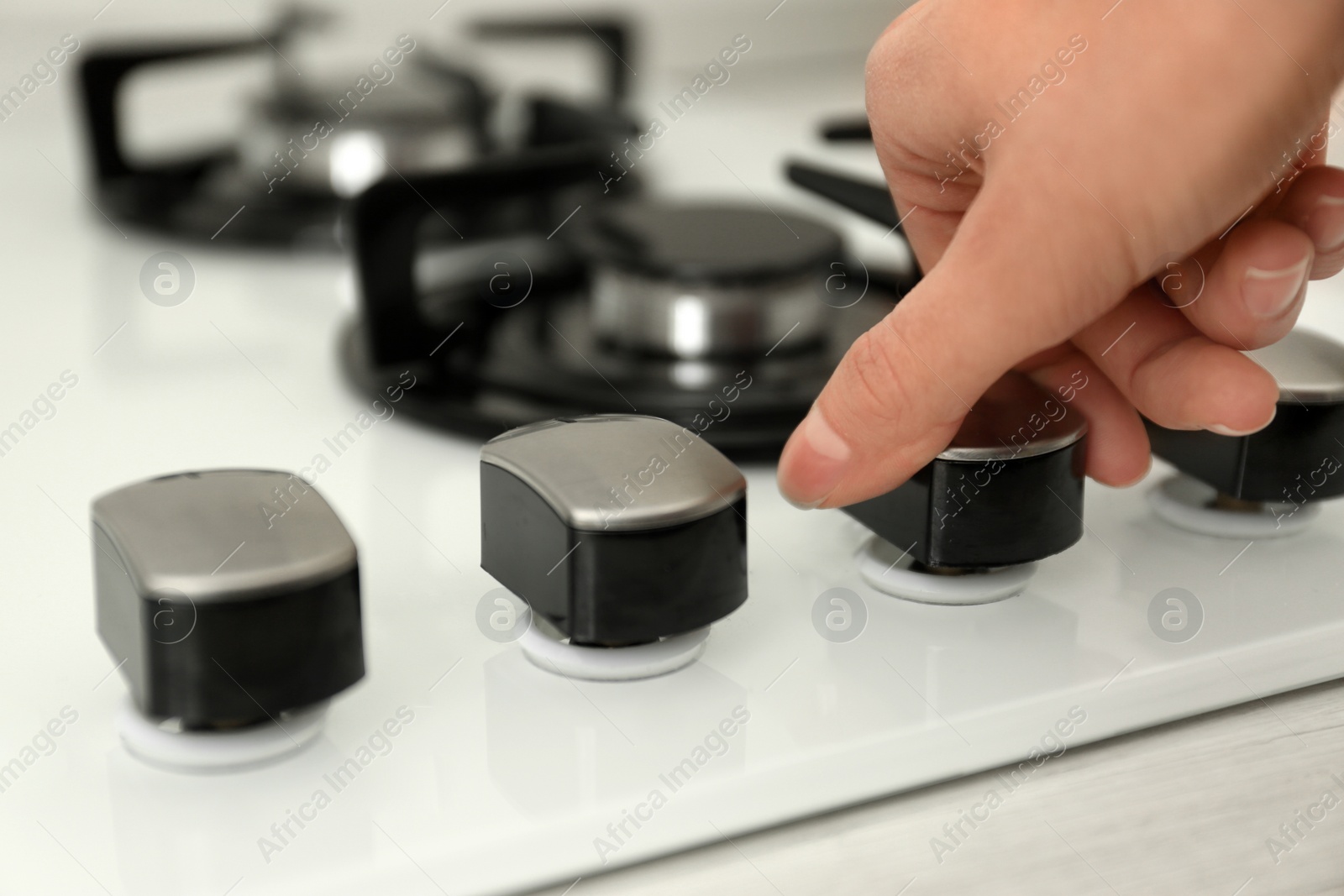 Photo of Woman regulating cooking mode on gas stove panel, closeup