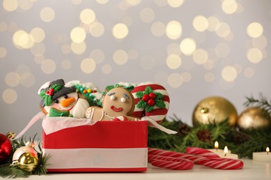 Photo of Sweet Christmas cookies and decor on white table against blurred festive lights