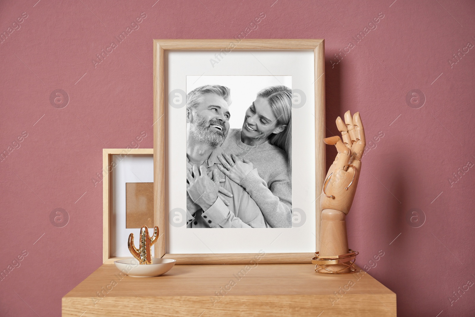 Image of Black and white family portrait of man and woman in photo frame on table near color wall