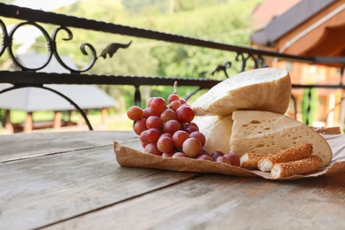 Photo of Delicious cheese and ripe grape on wooden table