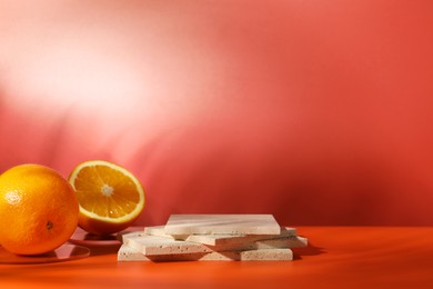 Photo of Presentation for product. Podium and tasty fresh oranges on red background, space for text