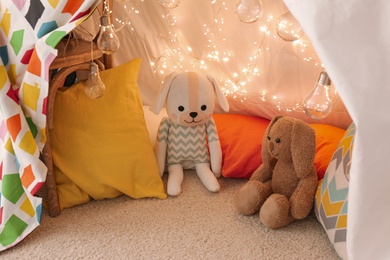 Play tent with toys and pillows indoors, closeup. Modern children's room interior