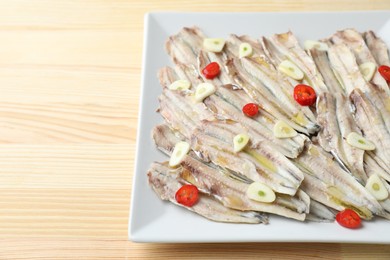 Photo of Tasty pickled anchovies with garlic and chili pepper on wooden table, closeup. Space for text