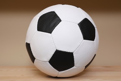 Soccer ball on wooden table near beige wall. Sports equipment