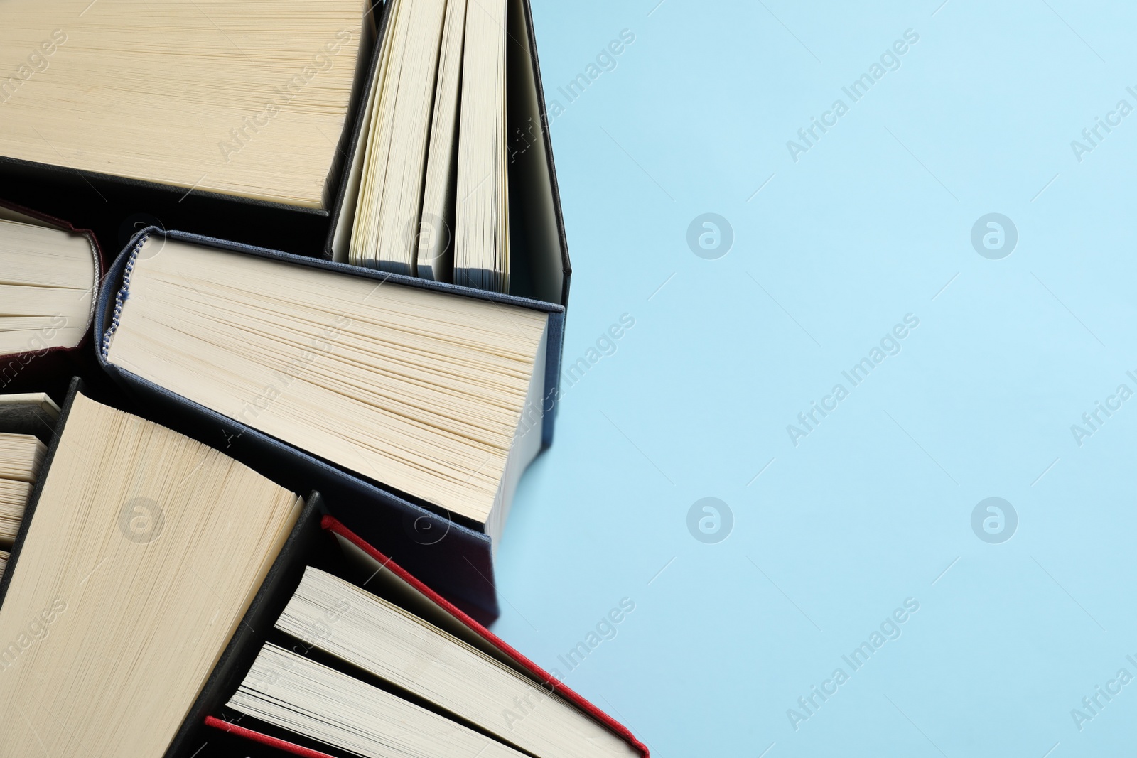 Photo of Many hardcover books on light blue background, top view. Space for text