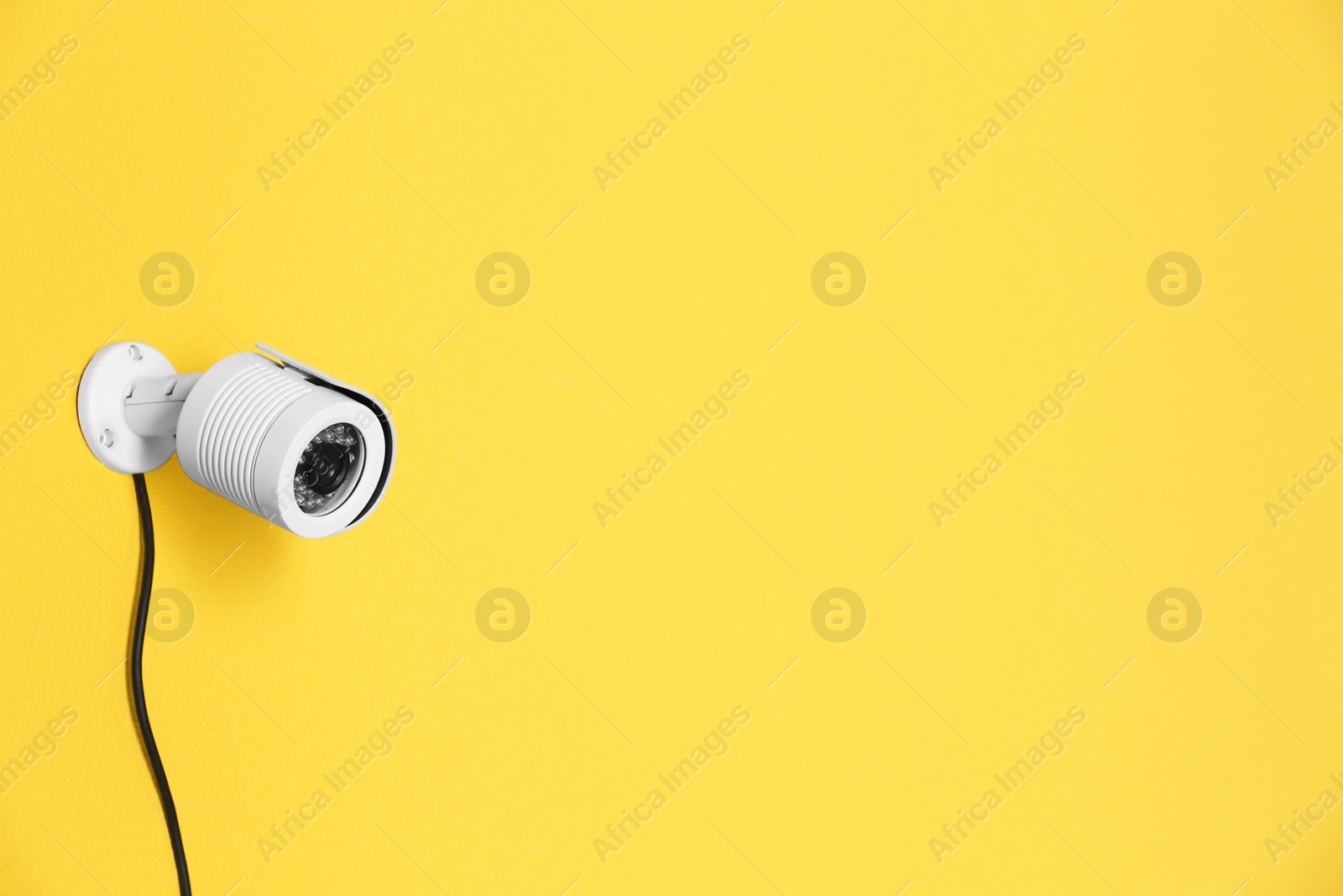 Photo of Modern security CCTV camera on color wall