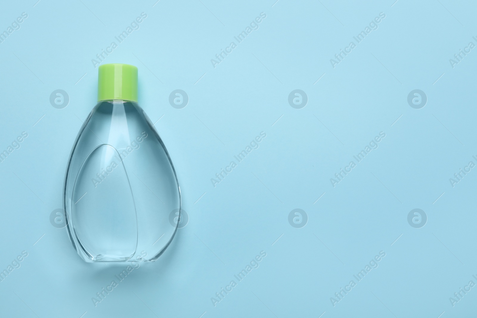 Photo of Bottle of baby oil on light blue background, top view. Space for text