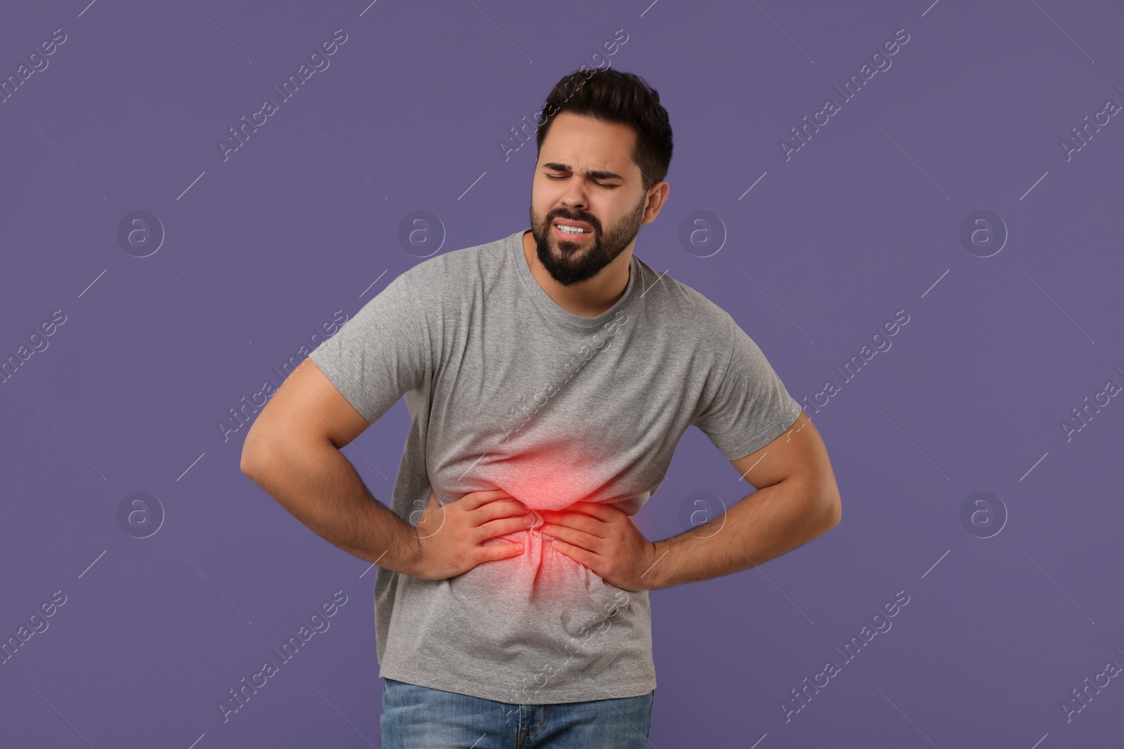 Image of Man suffering from stomach pain on purple background