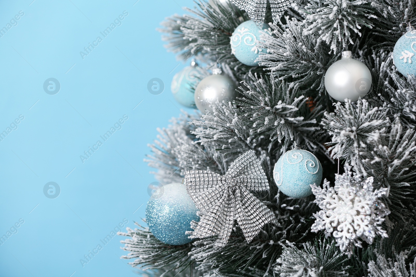 Photo of Beautiful Christmas tree with decor against light blue background, closeup. Space for text