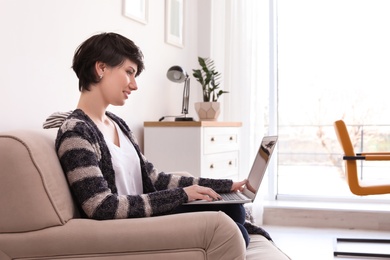 Photo of Young woman working with laptop at home