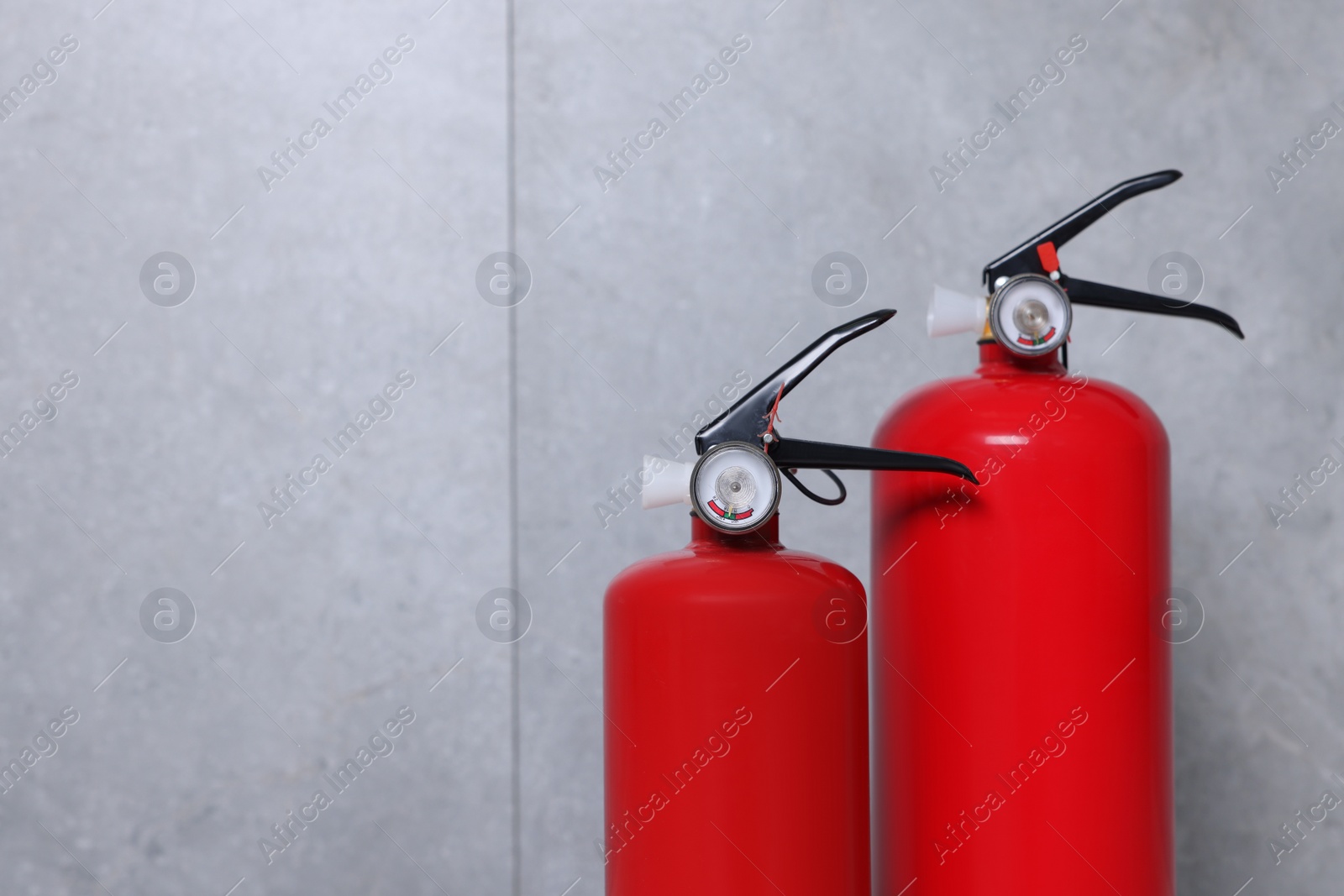 Photo of Fire extinguishers near grey wall, space for text