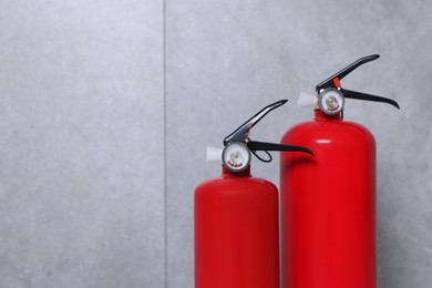 Photo of Fire extinguishers near grey wall, space for text