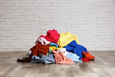 Pile of dirty clothes on floor near brick wall