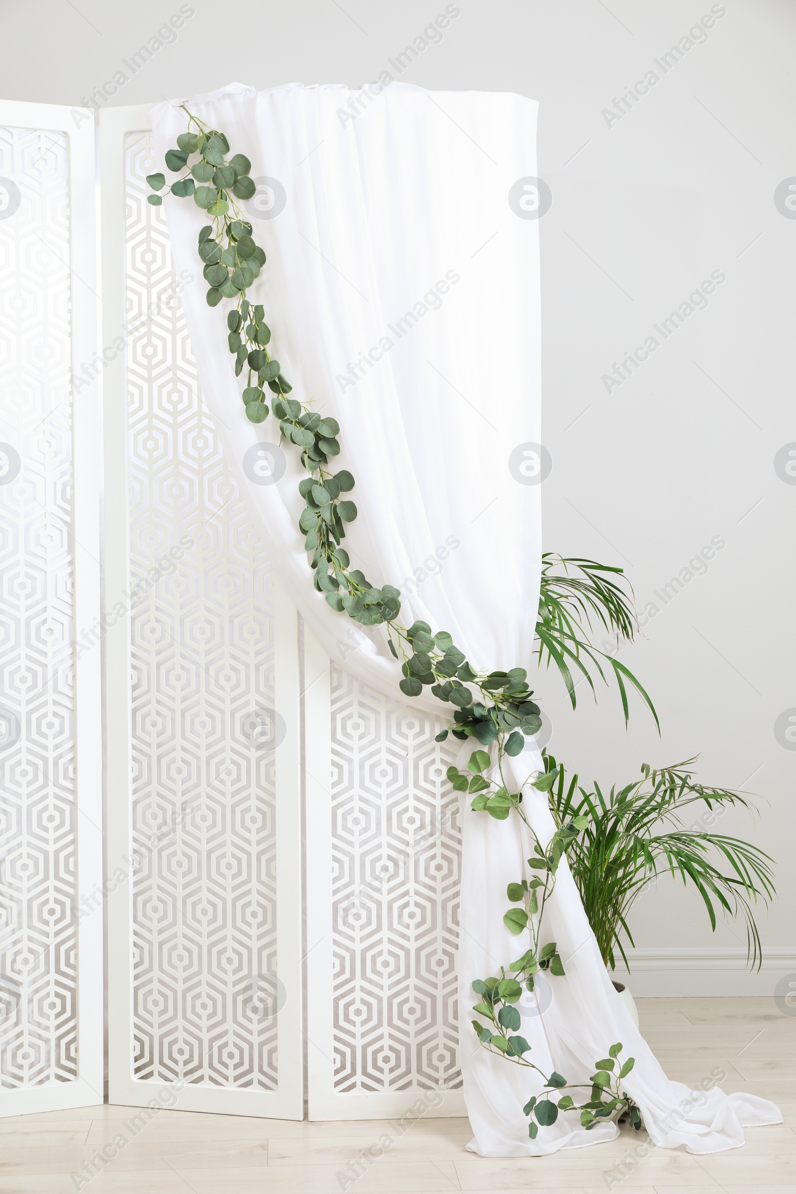 Photo of Stylish photo zone with white folding screen and floral decor indoors