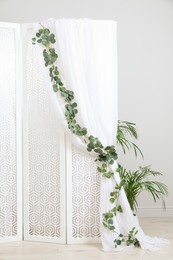 Photo of Stylish photo zone with white folding screen and floral decor indoors