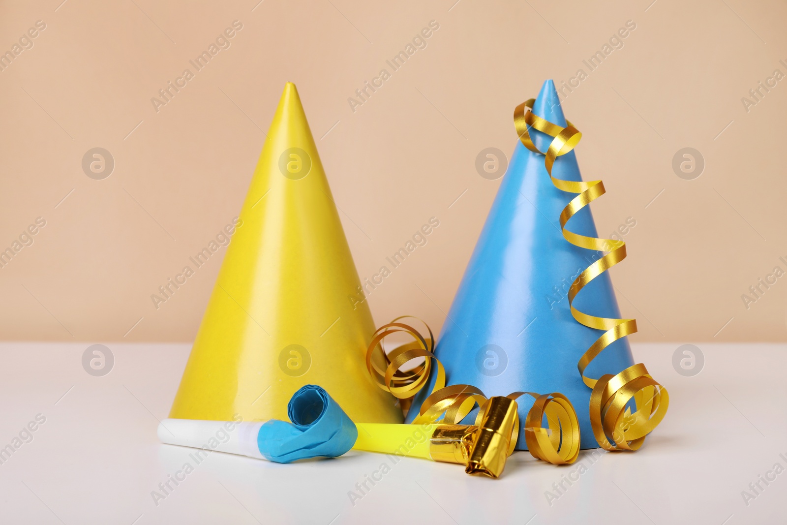 Photo of Colorful party hats, streamers and blowers on white table. Birthday celebration