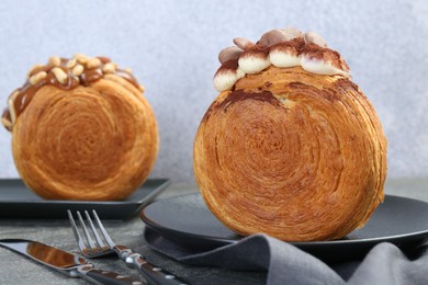 Photo of Crunchy round croissants on grey table, closeup. Tasty puff pastry