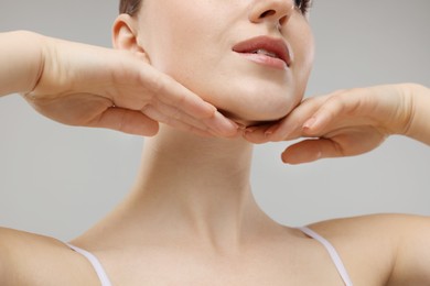 Photo of Woman touching her chin on grey background, closeup