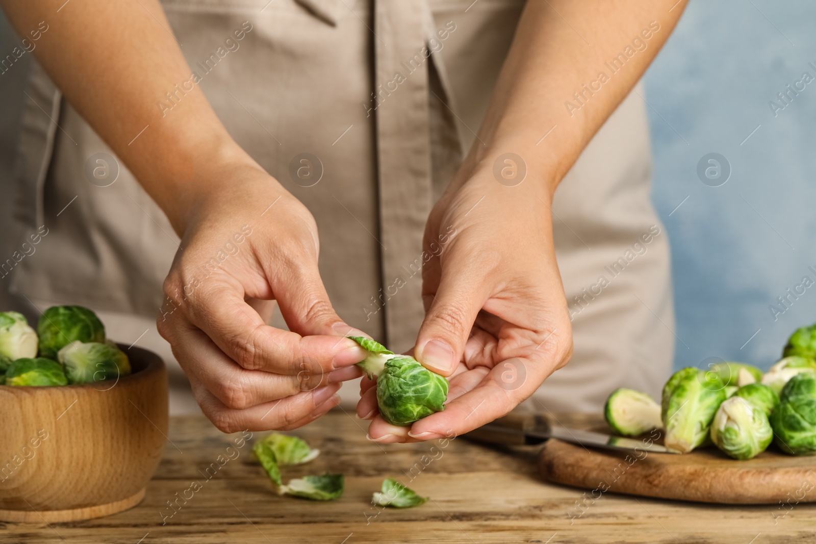 Photo of Woman peeling Brussels sprout at wooden table, closeup