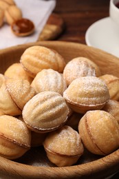 Delicious nut shaped cookies with boiled condensed milk and powdered sugar in wooden table, closeup
