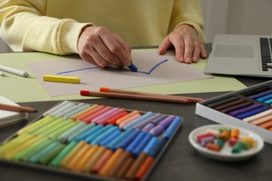 Photo of Artist drawing with soft pastels at table indoors, closeup