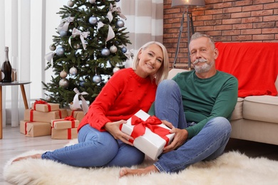 Mature couple with Christmas gift box at home