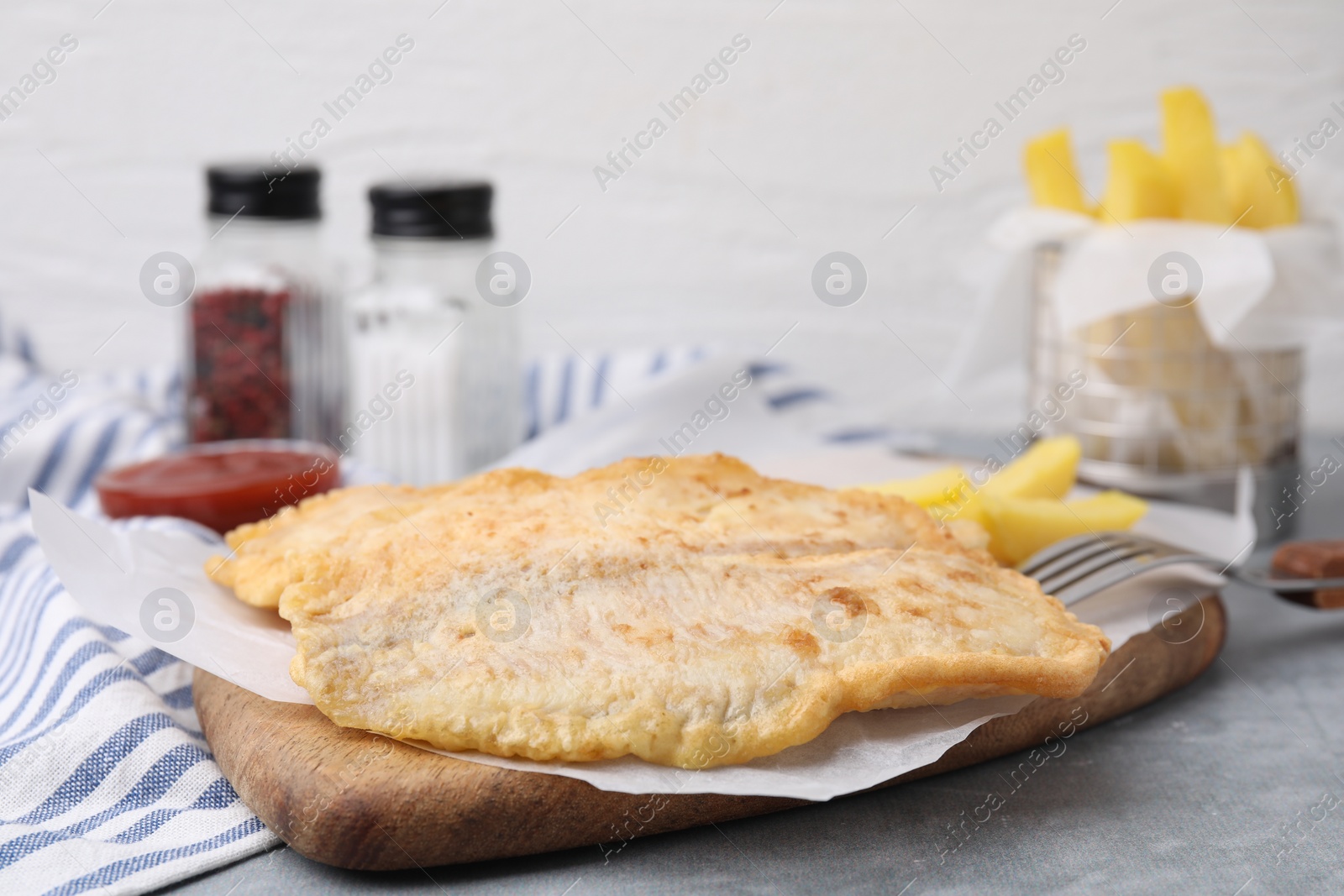 Photo of Delicious fish and chips served on gray table, closeup