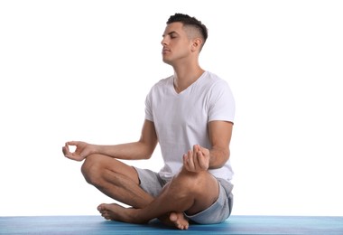 Photo of Handsome man meditating on yoga mat against white background