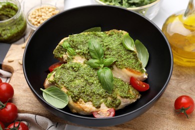 Photo of Delicious chicken breasts with pesto sauce, tomatoes and basil on table, closeup