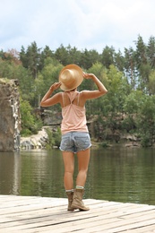 Photo of Young woman on wooden pier near lake. Camping season