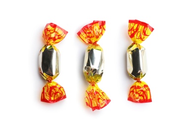 Delicious candies wrapped in foil on white background, top view