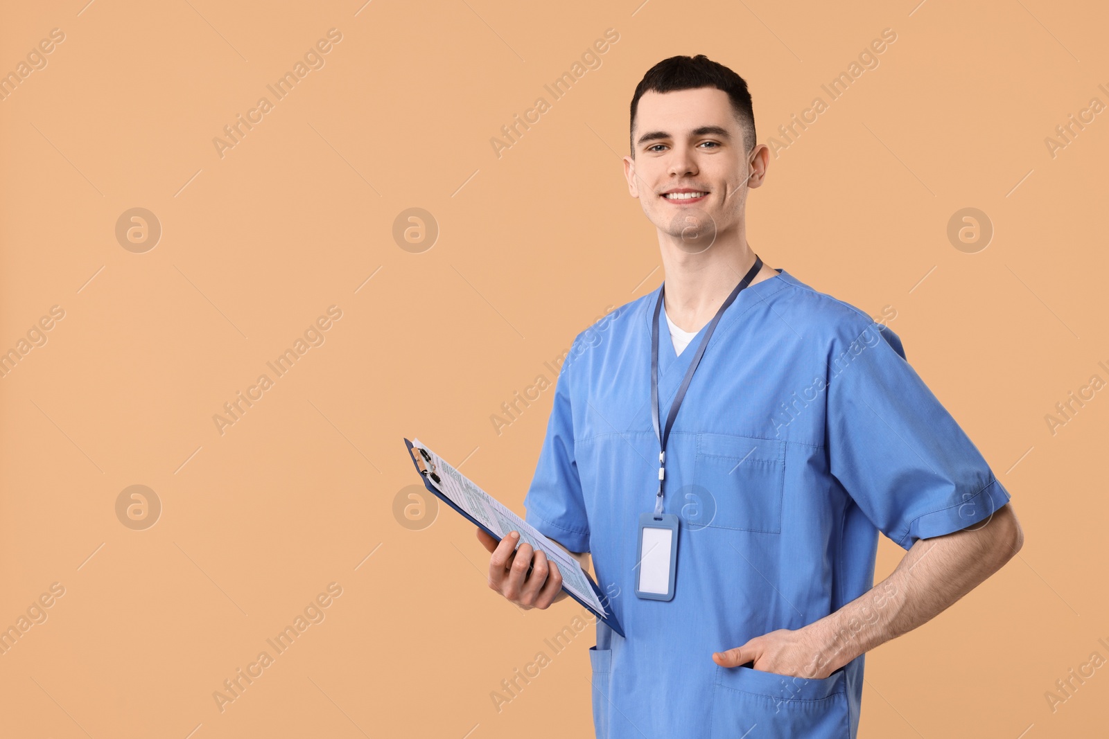 Photo of Portrait of smiling medical assistant with clipboard on beige background. Space for text