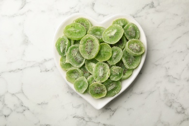 Photo of Plate with slices of kiwi on marble background, top view. Dried fruit as healthy food