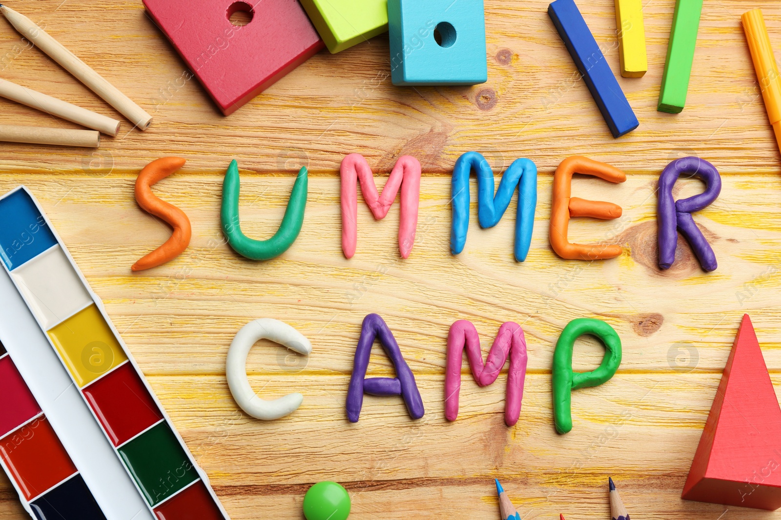 Photo of Flat lay composition with phrase SUMMER CAMP made of modelling clay on wooden background