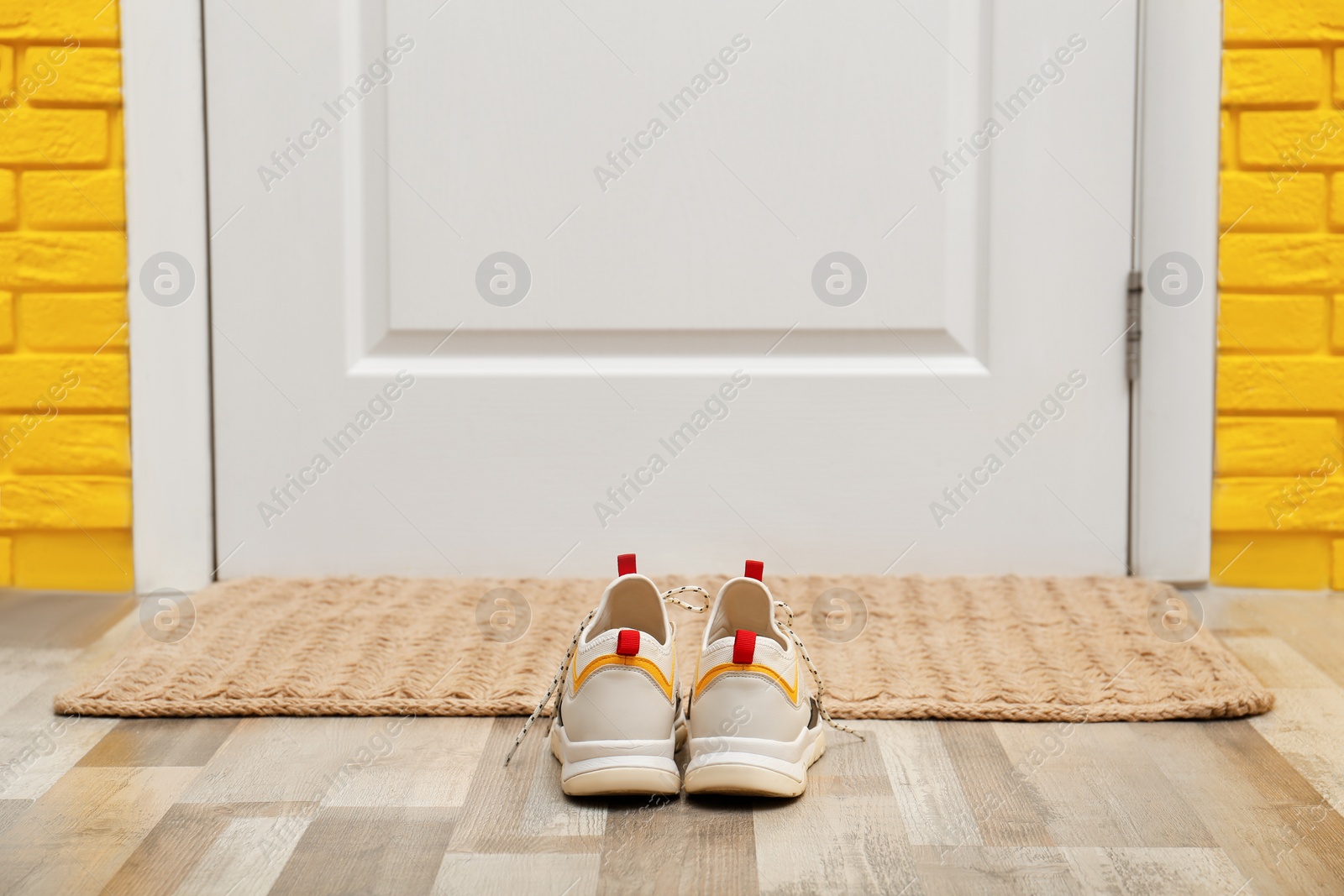 Photo of Shoes and mat near door in hallway