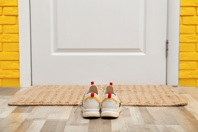 Photo of Shoes and mat near door in hallway