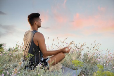 Photo of Man meditating in meadow near river. Space for text