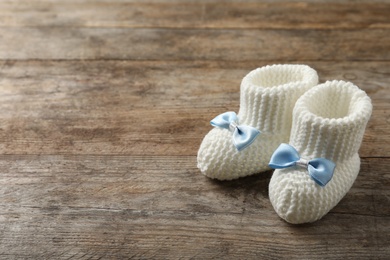 Handmade baby booties on wooden background. Space for text