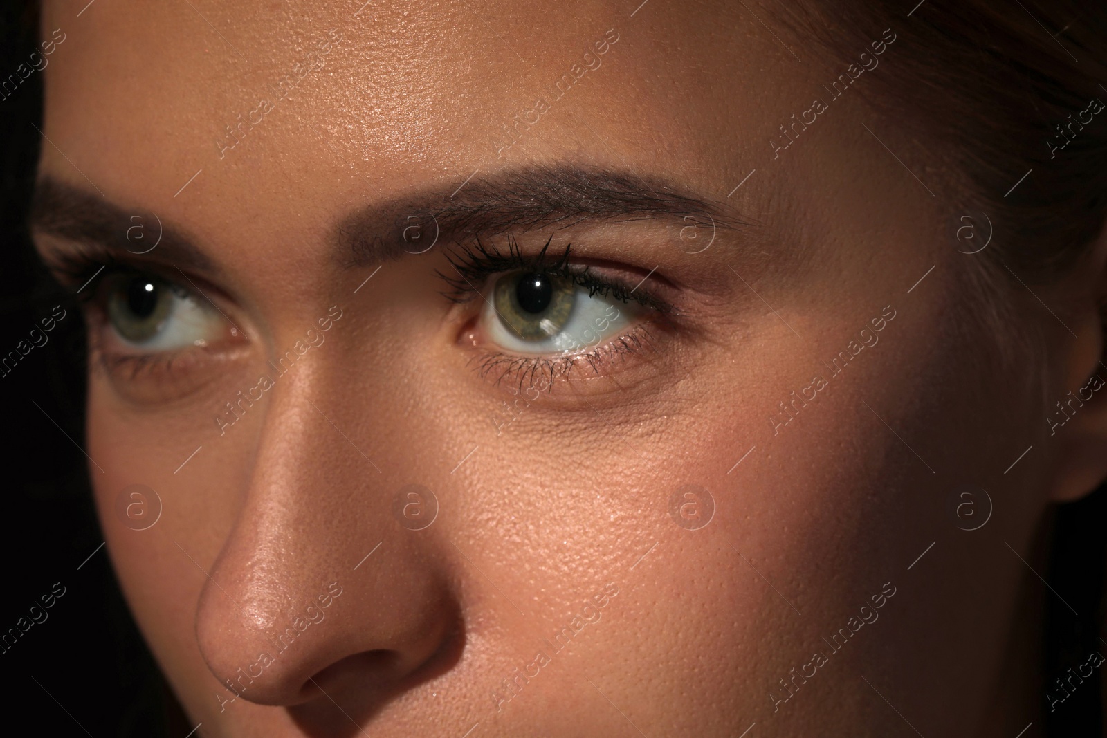 Photo of Evil eye. Young woman with scary eyes on black background, closeup